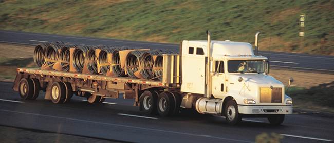 Professional flatbed truck driver securing cargo with chains and straps