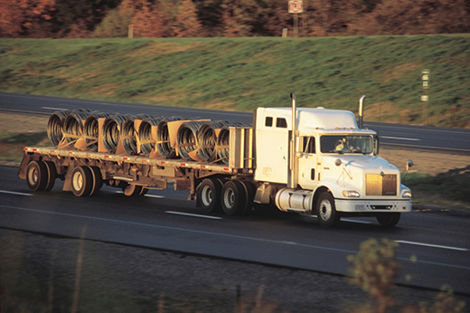 Professional flatbed truck driver securing cargo with chains and straps