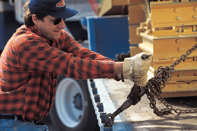 professional truck driver securing flatbed freight with chains